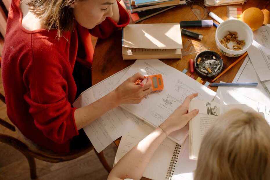 Two students engaged in studying at a table with textbooks, notes, and stationery.