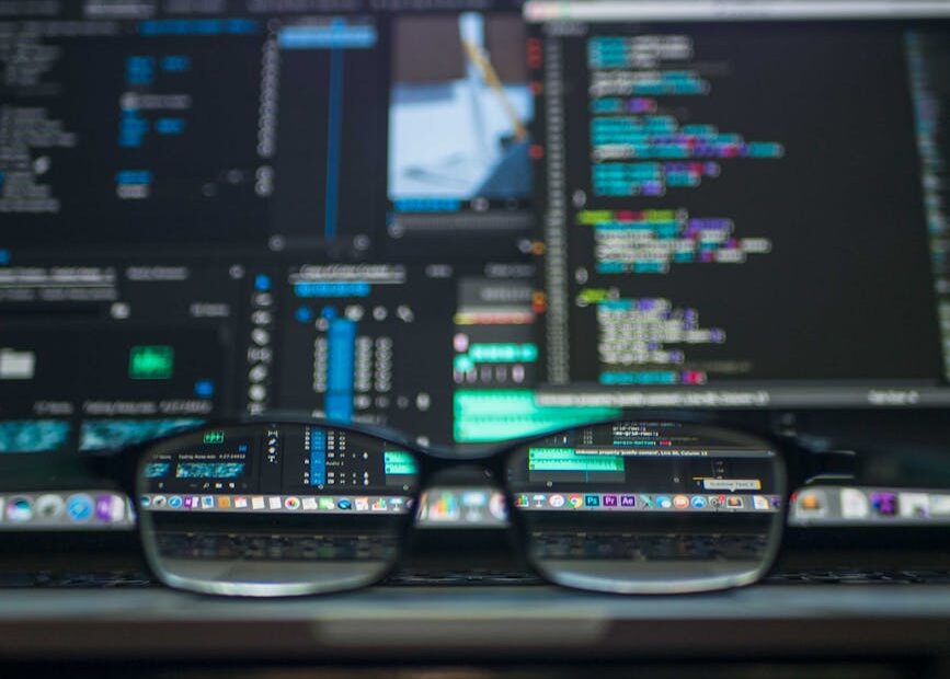 Eyeglasses reflecting computer code on a monitor, ideal for technology and programming themes.