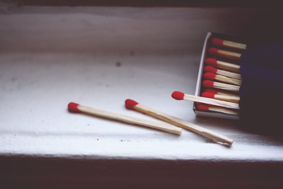 A close-up image of red tipped matchsticks resting on a white surface, with copy space.