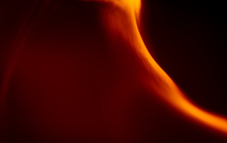 Dynamic abstract art featuring an orange flame-like light pattern against a dark background.
