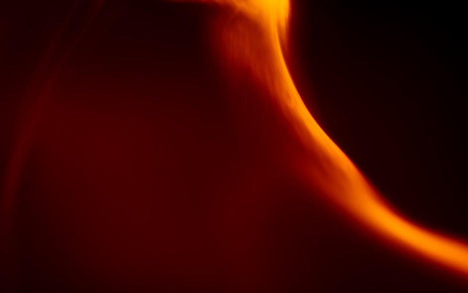 Dynamic abstract art featuring an orange flame-like light pattern against a dark background.