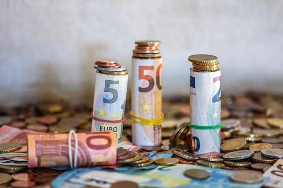 Close-up of rolled Euro banknotes and coins on a table, symbolizing finance and savings.