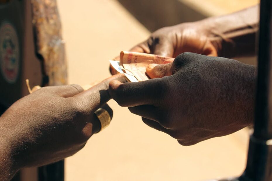 A detailed close-up of two hands exchanging paper currency outdoors, highlighting personal finance.