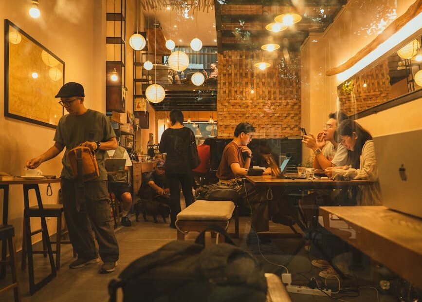 Warm and inviting coffee shop interior with people working and socializing, evening ambiance.