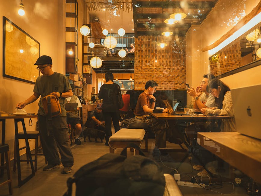 Warm and inviting coffee shop interior with people working and socializing, evening ambiance.